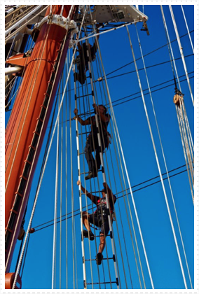 Sailors climb aloft to set the sails